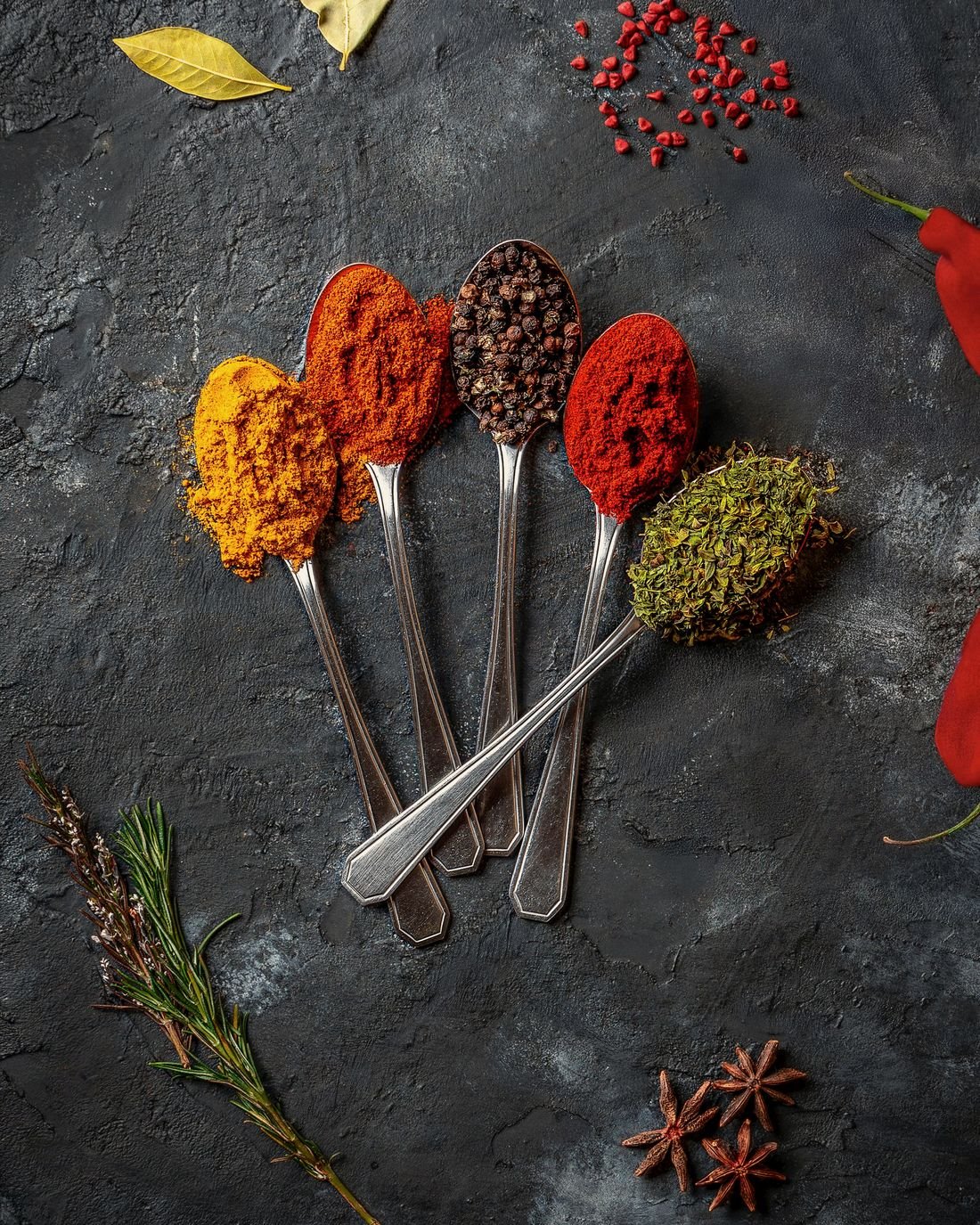 Spoons of Indian spice powders on dark slate